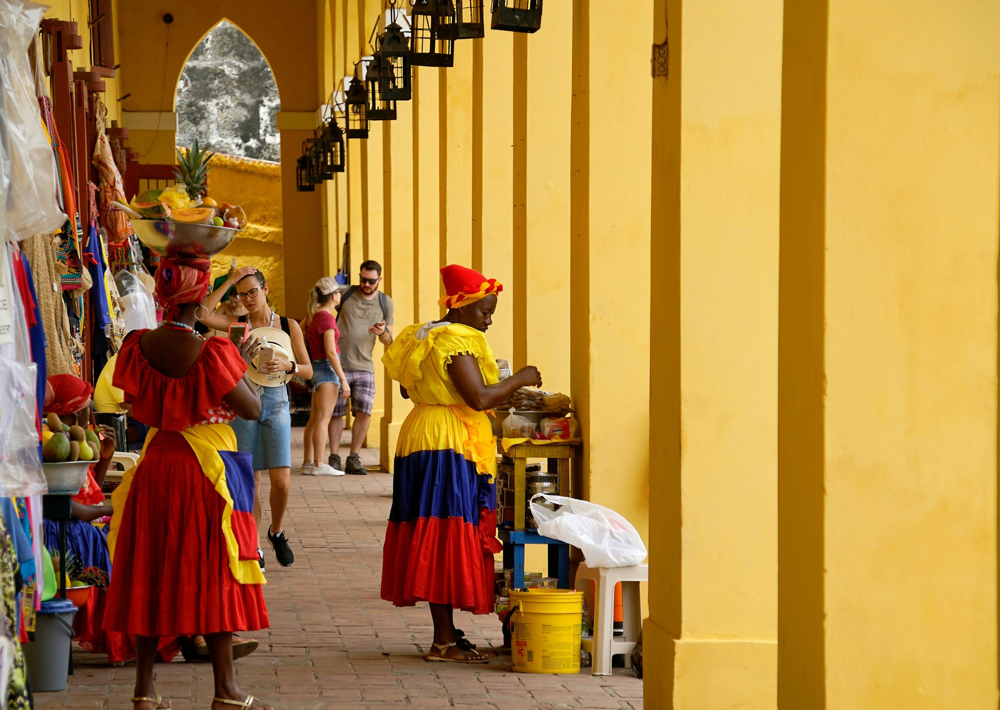 People walking through a yellow colonial corridor in Colombia.